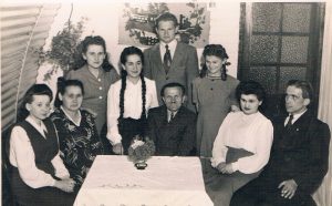 A black and white photograph of the Buczek Family sitting around the table in their Nissen hut