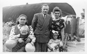 A black and white photograph of the Buczek family standing outside Site 7 Nissen hut