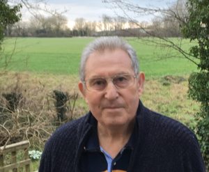 A photograph of Jan Baliszewski standing in front of a field where Site 8 and Site 7 once stood